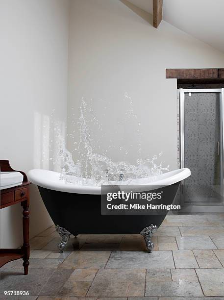 splash of water in claw-foot bath - baignoire-sur-pieds photos et images de collection