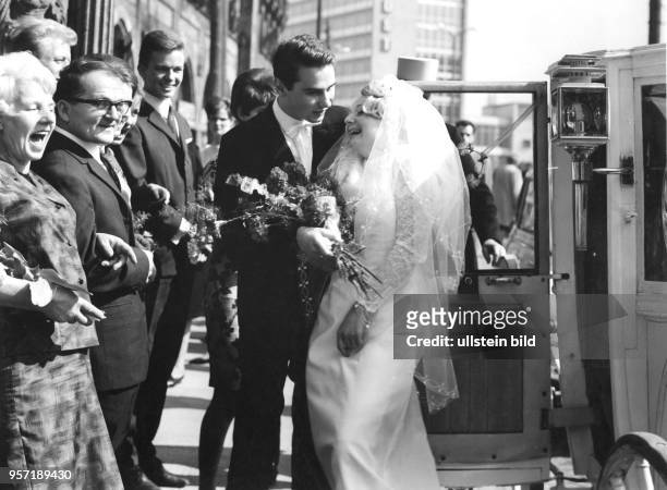 Ein junges Brautpaar steht vor seiner Hochzeitskutsche vor dem Rathaus in Karl-Marx-Stadt, aufgenommen 1968. Die Verwandten und Freunde freuen sich...