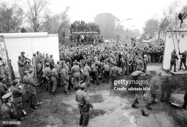 Grenzsoldaten der DDR fegen und befestigen am Potsdamer Platz nach dem Abbruch von Mauerteilen den Boden für einen provisorischen Grenzdurchgang,...