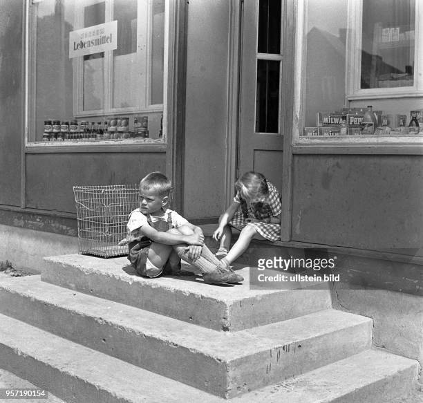 Auf der Treppe vor einem Lebensmittelladen in Metelsdorf bei Wismar sitzen zwei Kinder und langweilen sich, aufgenommen im Sommer 1963.