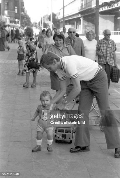 Ein Vater stützt seinen Sohn bei den ersten Laufschritten in der Schönhauser Allee. Der Junge zieht dabei seinen Kipper, ein beliebtes Spielzeug in...