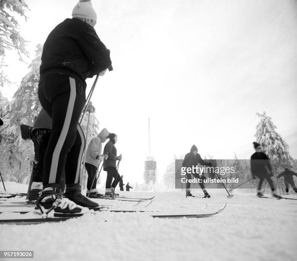 Skiläufer auf einem verschneiten Hang im Skigebiet am Großen Inselsberg bei Tabarz im Thüringer Wald, im Hintergrund der Sendeturm, aufgenommen im...