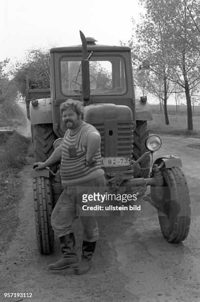 Ein recht beleibter Traktorist posiert vor seinem Fahrzeug, aufgenommen zu Pfingsten am in Hübitz im Mansfelder Land. Per Anhänger transportiert er...