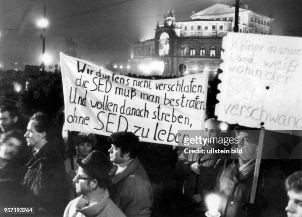 Dresdner Bürger haben sich im November 1989 auf dem Theaterplatz vor der Semperoper in Dresden versammelt und demonstrieren mit Transparenten gegen...