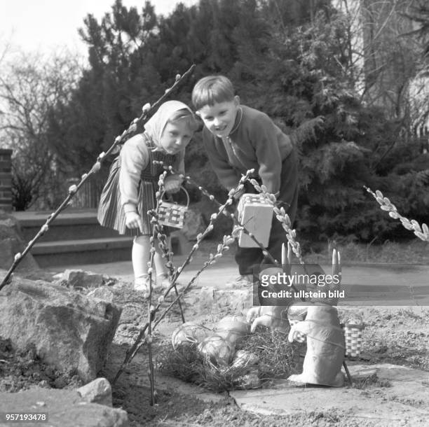 Ein kleiner Junge und ein kleines Mädchen mit Körbchen beim Suchen von Ostereiern, Foto vom .