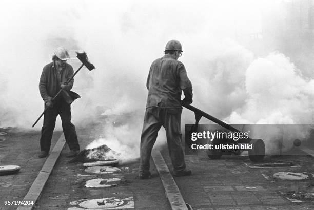 Zwei Arbeiter umgeben von austretenden Abgasen beim Abdichten von Brennkammern im Gaswerk an der Dimitroffstraße/Ecke Greifswalder Straße im...