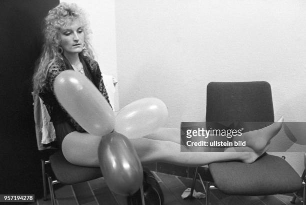Mit Luftballons und ausgestreckten Beinen sitzt eine junge Frau, eine Bewerberin bei einer Miss-Wahl, im Kulturhaus Wabe im Wohngebiet...