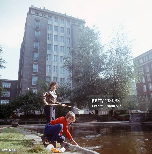 Zwei Jungen spielen an einem kleinen Gewässer vor dem Hochhaus an der Weberwiese im Berliner Stadtbezirk Friedrichshain, undatiertes Foto aus dem...