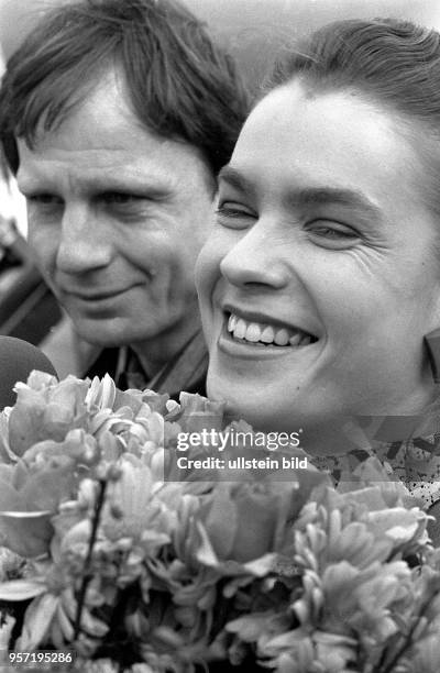 Die frischgebackene Eiskunstlauf-Olympiasiegerin Katarina Witt mit einem großen Blumenstrauß bei ihrer Ankunft auf dem Ostberliner Flughafen...