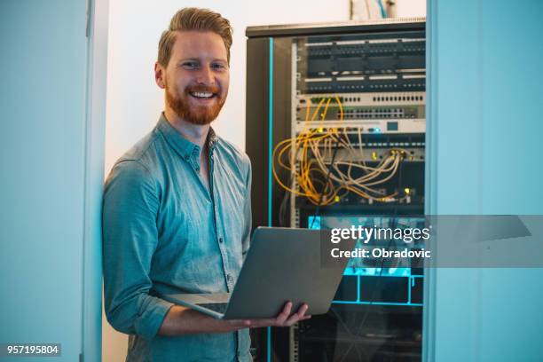 male caucasian it technician using laptop in server room - computer equipment stock pictures, royalty-free photos & images