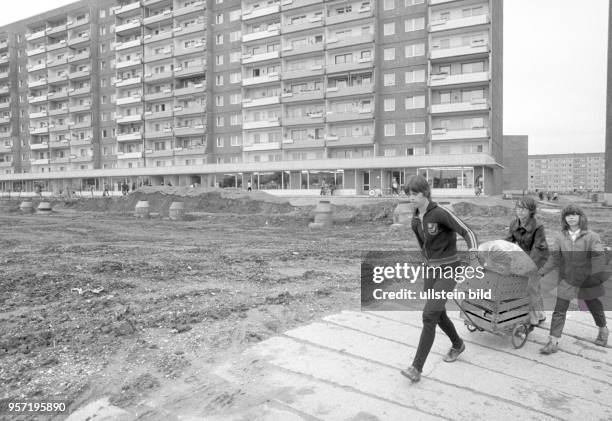 Über eine provisorischen Plattenweg im Neubaugebiet Leipzig-Grünau ziehen Einwohner einen kleinen Lastwagen, undatiertes Foto von 1984. Jeder fertig...