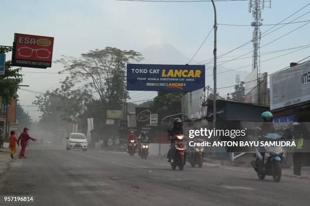 Indonesian motorists commute along an ash covered road after mount Merapi erupted, in Sleman on May 11, 2018. - Indonesian villagers living in the...