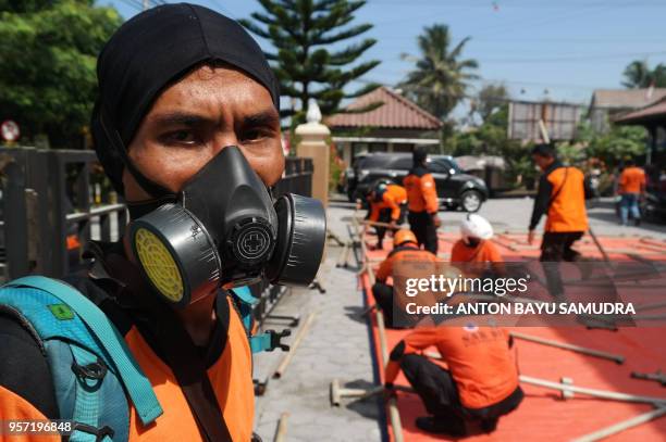 An Indonesian member of a Search and Rescue team wears a mask as they build a temporary shelter for people in Sleman on May 11 after after mount...