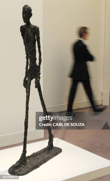 Man walks past a sculpture by Swiss artist Alberto Giacometti entitled 'L'Homme qui marche I' at Sotheby's auction house, in London, on January 12,...