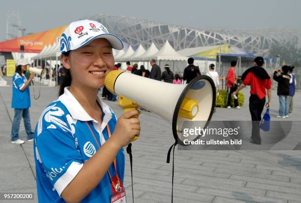 Mit Megaphon werden die Besucher des Olympiageländes "Olympic Green", das im Norden von Peking liegt, vor dem Eingang begrüßt, aufgenommen im Oktober...