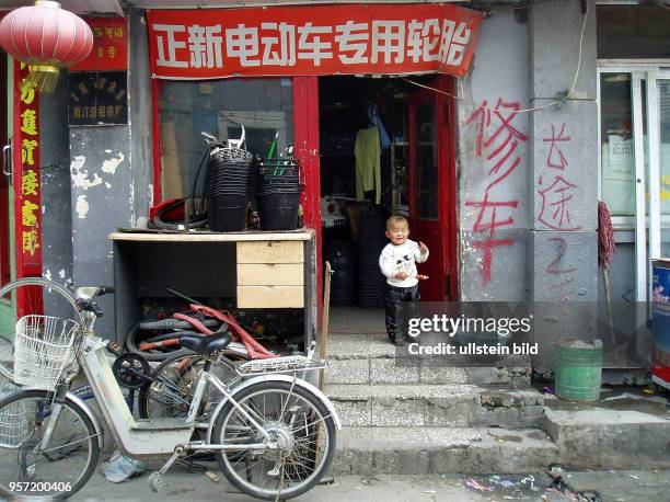 In einer Gasse im Pekinger Altstadtviertel steht ein Kind in der offenen Tür eines kleinen Ladens, aufgenommen im Oktober 2008.