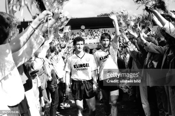 Die Dresdner Spieler Hans-Uwe Pilz und Andreas Trautmann gehen durch ein Blumenspalier, gebildet von Dresdner Fans. 45.000 Dynamo-Fans feiern am im...