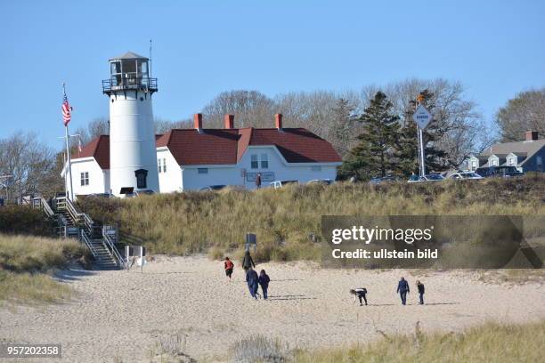 Spaziergänger unterhalb des Leuchtturms am Strand von Chatham auf der Halbinsel Cape Cod. Nur 4 Stunden Autofahrt von New York entfernt bieten die...