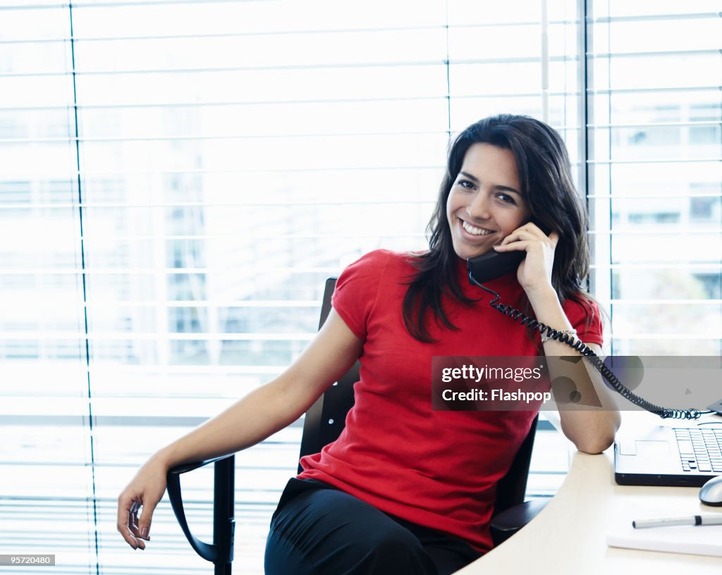 Portrait of woman talking on the telephone at work