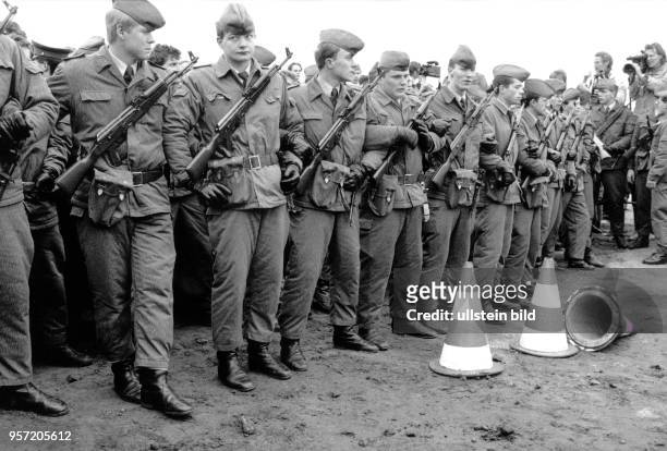 Mit Maschinenpistolen und Kampfausrüstung stehen Offiziersschüler des DDR-Wachregiments "Feliks Dzierzynski" untergehackt als Sperrlinie an der...