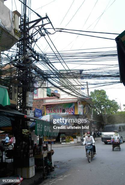 Blick auf ein wahres Gewirr von Stromkabeln an einer Straßenkreuzung in der Altstadt von Hanoi, der Hauptstadt der Sozialistischen Republik Vietnam,...