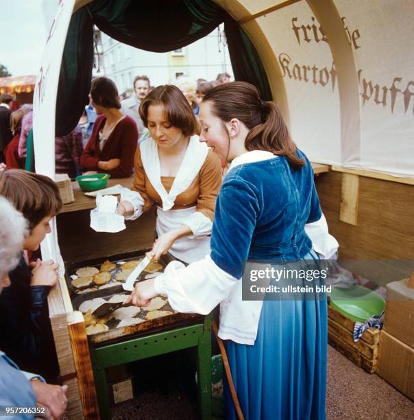 In historischen Kostümen verkaufen junge Frauen frische Kartoffelpuffer anlässliche einer Ausstellungseröffnung im Kloster Unser Lieben Frauen in...