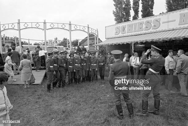 Sowjetische Militärangehörige posieren auf einem Jahrmarkt für ein Gruppenfoto, aufgenommen im Juni 1985 in Gerbstedt. Im Hintergrund besteigen...