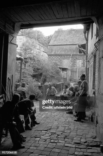 Männer sitzen in einem Hof alter Häuser in der Lutherstadt Eisleben und trinken Bier aus Flaschen, aufgenommen am .