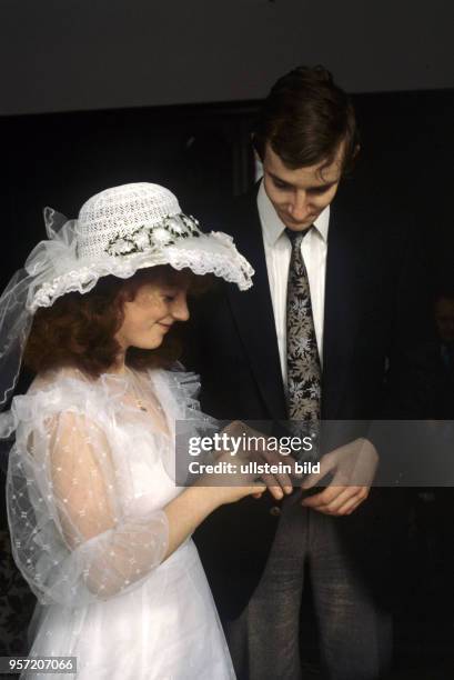 Eine Braut mit Spitzenhut steckt ihrem Bräutigam den Ehering an den Finger, aufgenommen bei einem Ball der Jungvermählten in Werder am .