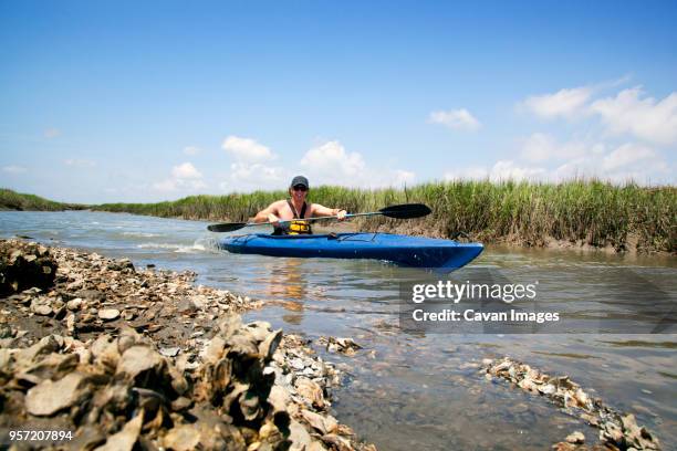 man kayaking in lake against sky - canoeing and kayaking stock pictures, royalty-free photos & images