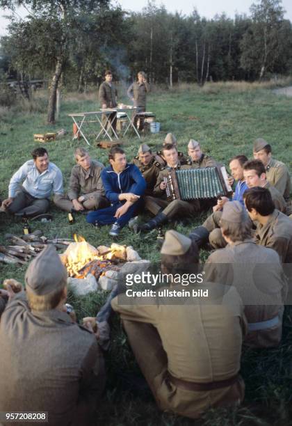 Soldaten der NVA und der sowjetischen Streitkräfte sitzen am Lagerfeuer und singen. Die Pioniere beider Armeen bauten im Rahmen einer gemeinsamen...