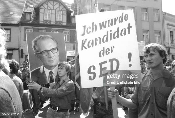 Bei einer Kundgebung in Eisleben im Mansfelder Land tragen FDJler große Fotos von SED-Parteichef Honecker, ein anderer junger Mann trägt ein Schild...