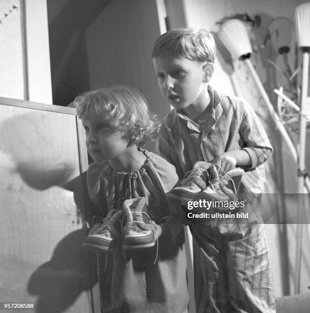 Ein kleines Mädchen und ein kleiner Junge in Nachtwäsche tragen ihre Schuhe für den Nikolaus zur Tür, undatiertes Foto vom Dezember 1963.