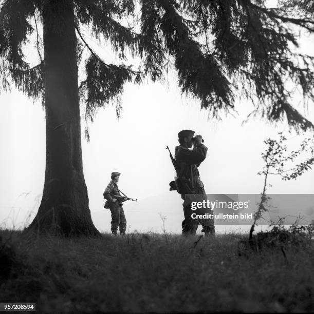 Zwei Grenzsoldaten der DDR-Grenztruppen der Nationalen Volksarmee der DDR bei einem Wachgang an der innerdeutschen Grenze bei Motzlar in der Rhön in...