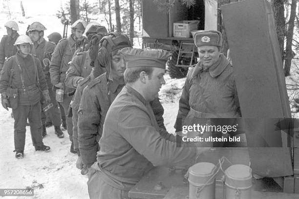 Soldaten der Nationalen Volksarmee im winterlichen Gelände bei der Verpflegung im Rahmen einer Übung, undatiertes Foto von 1981 bei Torgelow.