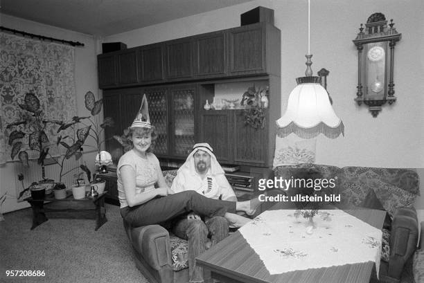 Zwei Karnevalisten posieren in ihrer Neubauwohnung im Ernst-Thälmann-Park in Berlin zwischen Schrankwand und Sitzeckel, aufgenommen 1987. Die...