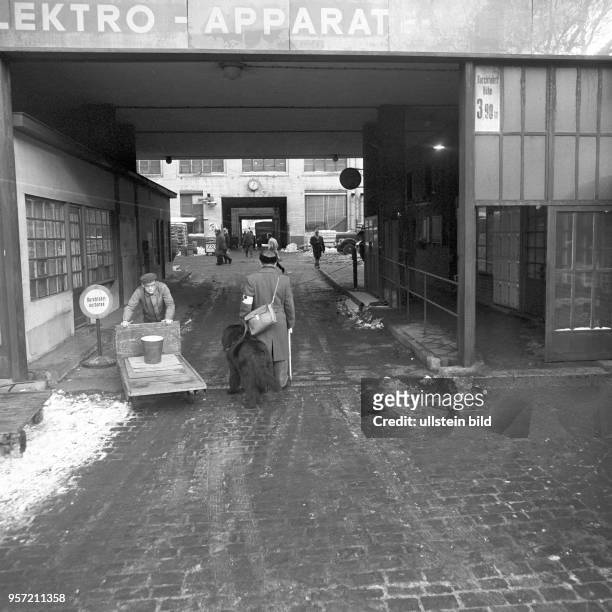 Ein blindes Mitglied der Brigade "Louis Braille" mit seinem Blindenhund am Eingang zum VEB Elektro-Apparate-Werke Berlin-Treptow "Friedrich Ebert" ,...