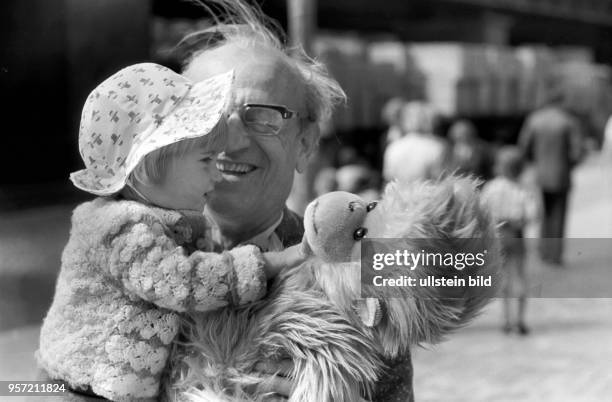 Ein Großvater mit seinem Enhelkind und einem großen Plüschtier, aufgenommen 1976 in der Schönhauser Allee in Berlin Prenzlauer-Berg.