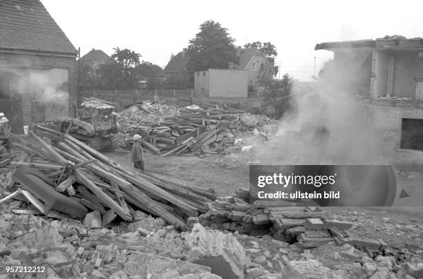 Alte Holzbalken abgerissener Gebäude sind gestapelt, Mauern werden niedergerissen, der Ort Magdeborn weicht dem anrückenden Braunkohletagebau...