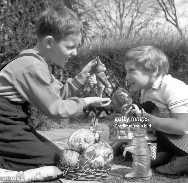 Ein Junge und ein Mädchen haben zum Osterfest in einem Garten Ostereier gesucht und haben die gefundenen Schätze, bunte Pappostereier und Osterhasen...