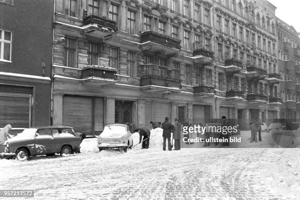 Freiwillige Helfer schaufeln Schnee zwischen abgestellten Fahrzeugen in einer Straße in Berlin Prenzlauer Berg, undatiertes Foto vom Februar 1979....