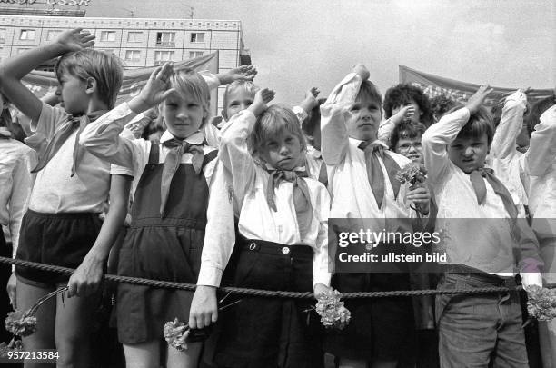 Pioniere grüßen mit dem Pioniergruß Mitglieder der Kampfgruppen der DDR bei einem Appell in der Karl_Marx_Allee in Berlin anläßlich des 25....