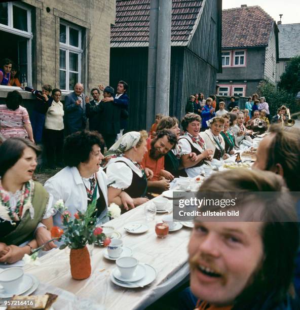 An langen Tischen auf der Dorfstraße sitzen die Nachbarn zusammen und essen und trinken Selbtsgemachtes beim Volksfest Grasedanz in Hüttenrode im...
