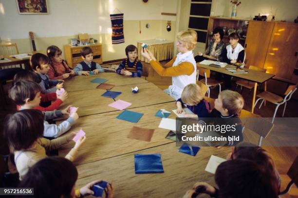 Kinder falten in einem Kindergarten aus farbigen Papieren dreidimensionale Formen und werden so nach dem Vorbild des Pädagogen Friedrich Fröbel...
