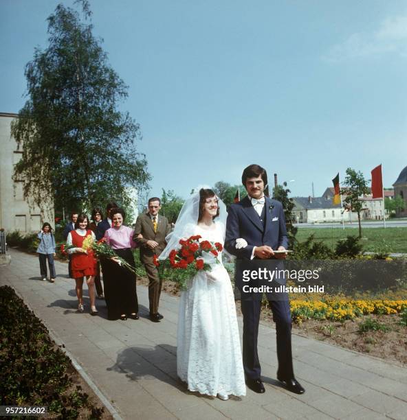 Ein Hochzeitspaar, die Braut mit einem Strauß roter Nelken, einem weißen Brautkleid und einem weißen Schleier, in Schwedt, undatiertes Foto aus dem...