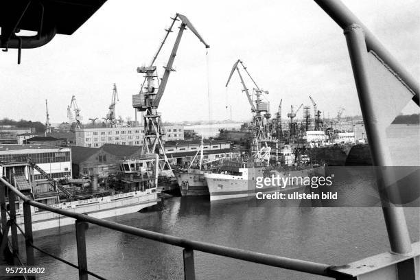 Schiffsreparatur und Neubau sind in der Rostocker Neptun Werft auf engstem Raum miteinander verknüpft, aufgenommen in den 1980er Jahren. Während ein...