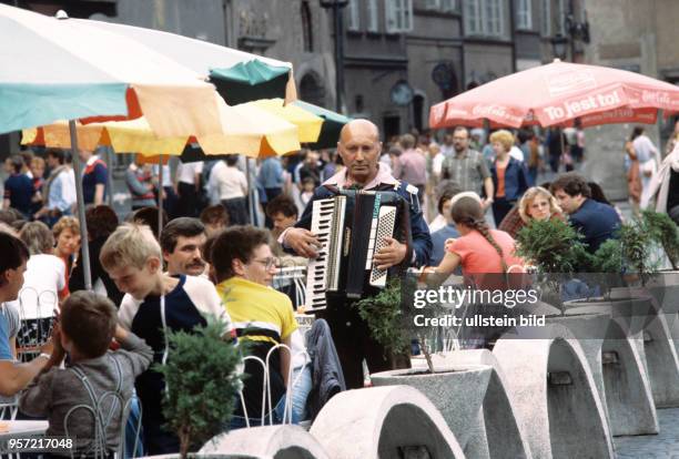 Ein Akkordeonspieler unterhält als Straßenmusikant die Gäste in einem Straßencafe in der Altstadt von Warschau, aufgenommen im Juni 1985.Im...