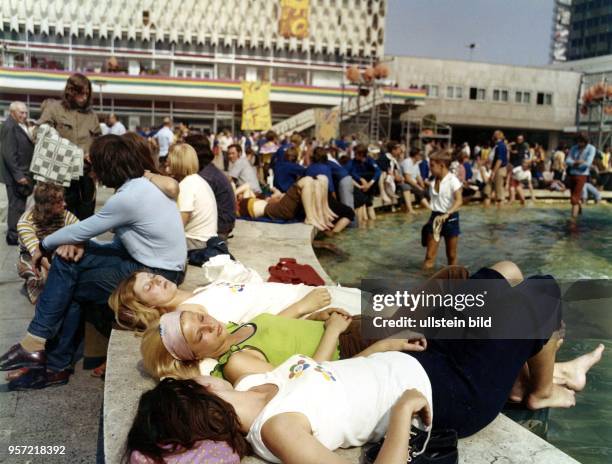 Jugendliche genießen die sommerlichen Temperaturen und entspannen am Brunnen der Völkerfreundschaft auf dem Berliner Alexanderplatz, aufgenommen...