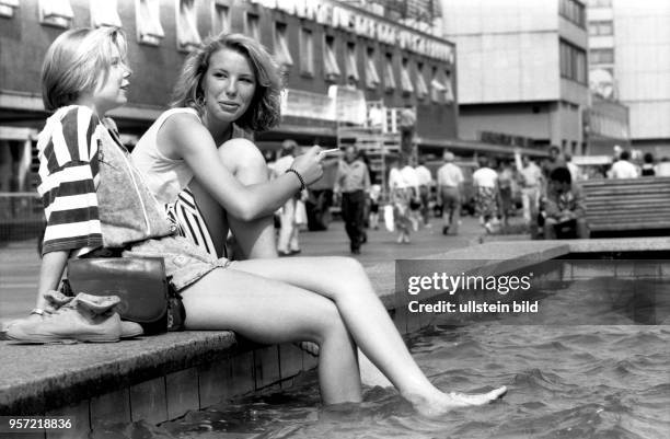 Im August 1990 sitzen zwei junge Frauen an einem der vielen Brunnen in der Prager Straße in Dresden und genießen eine sommerliche Abkühlung....