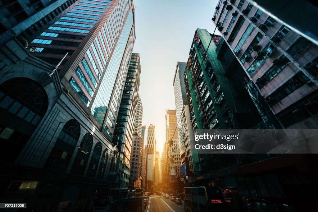 Busy traffic and dense commercial skyscrapers along the road in city downtown district, Hong Kong at sunrise